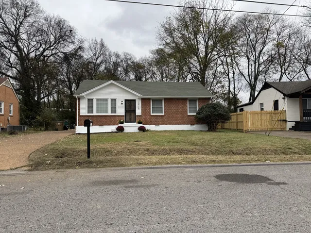 a front view of a house with a yard and large tree