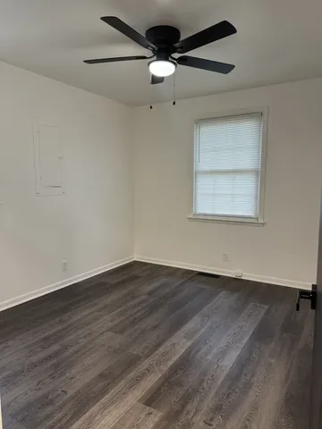 an empty room with wooden floor ceiling fan and windows