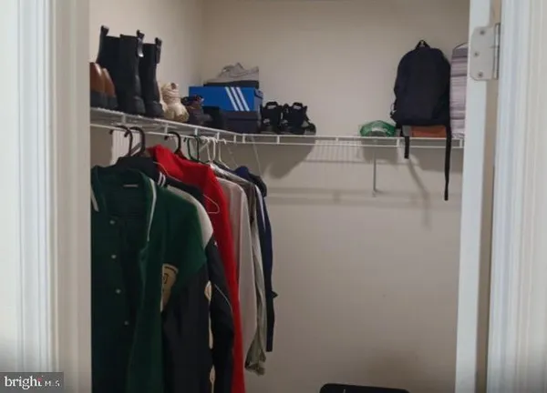 a view of walk in closet with clothes and shoes