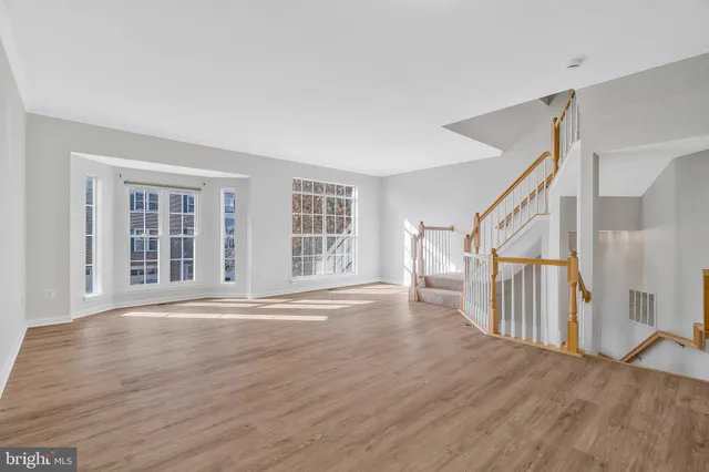a view of an empty room with wooden floor and stairs