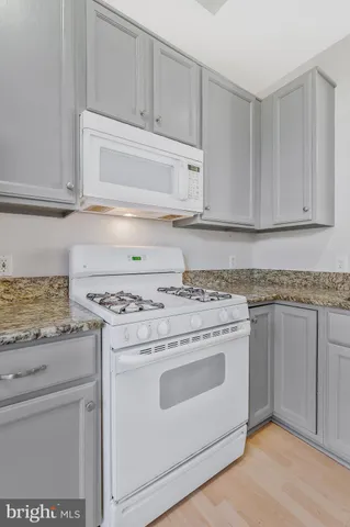 a kitchen with granite countertop white cabinets and white appliances