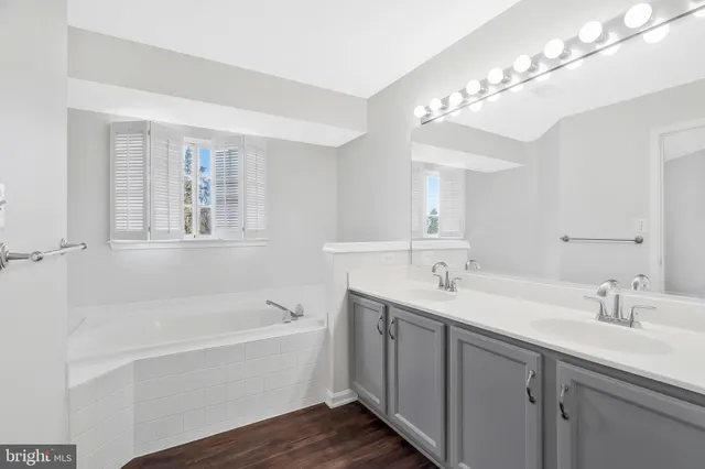 a bathroom with a tub a sink and mirror