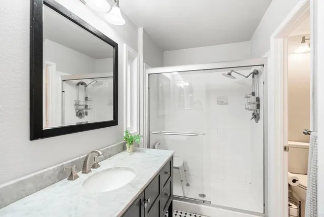 a bathroom with a granite countertop sink mirror and a shower