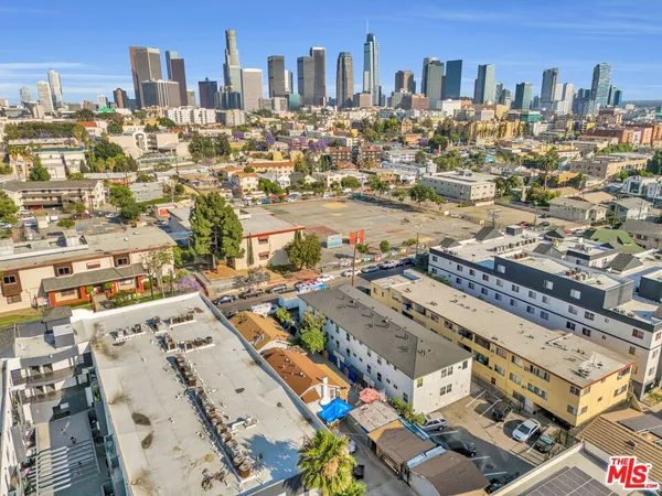 an aerial view of a city with lots of residential buildings and ocean view in back