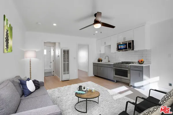 a kitchen with stainless steel appliances granite countertop a stove a sink dishwasher and a refrigerator with wooden floor