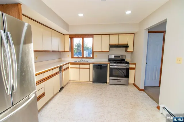 a kitchen with white cabinets stainless steel appliances and a window