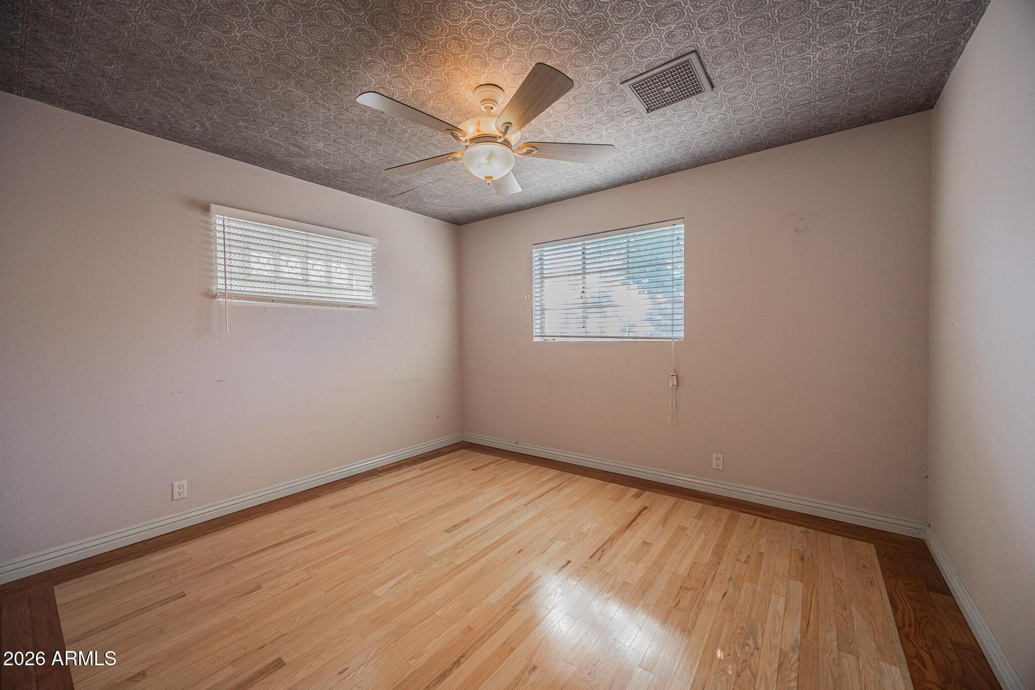 3137 North 4th Avenue Phoenix, AZ 85013 - Photo 22 of 36 an empty room with wooden floor fan and windows