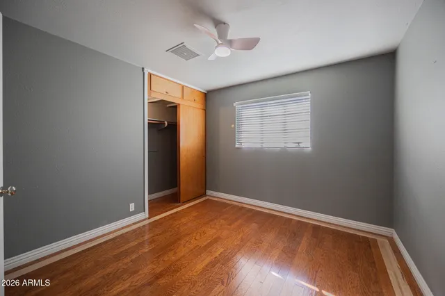 a view of empty room with wooden floor and fan