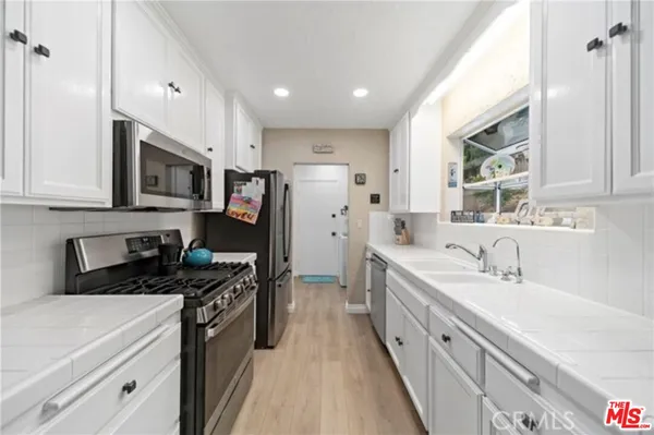 a kitchen with stainless steel appliances white cabinets a stove a sink and a microwave