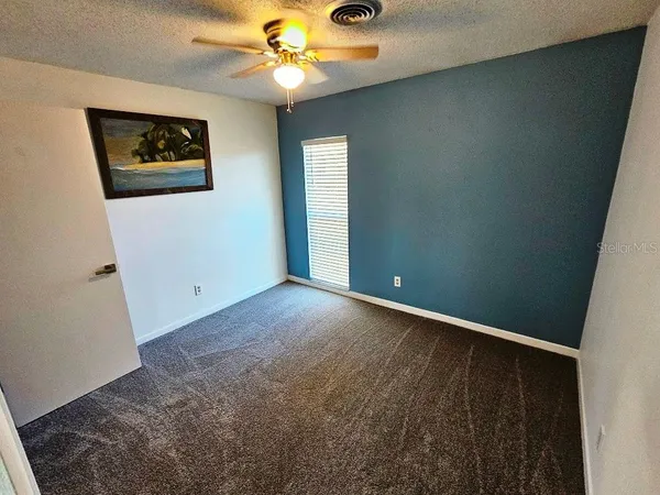 an empty room with windows and fan