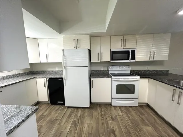 a kitchen with kitchen island granite countertop a sink stainless steel appliances and cabinets
