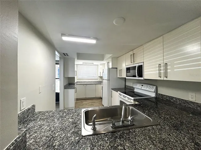 a kitchen with stainless steel appliances kitchen island granite countertop a refrigerator and a sink