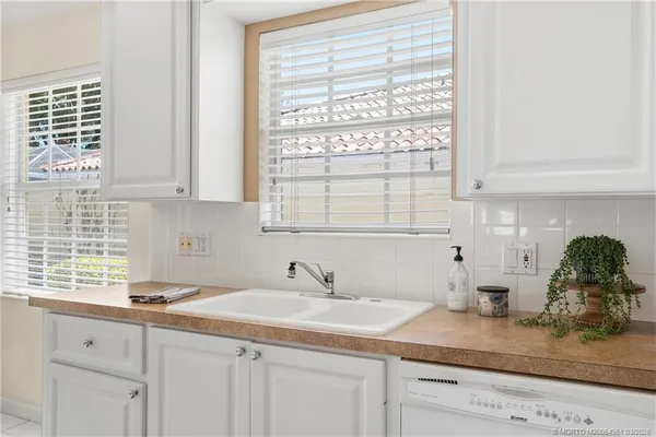 a kitchen with stainless steel appliances granite countertop white cabinets and a window