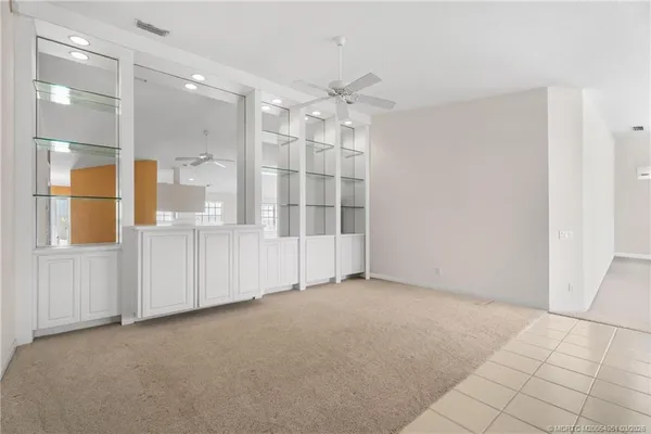en empty room with a white cabinet and chandelier fan
