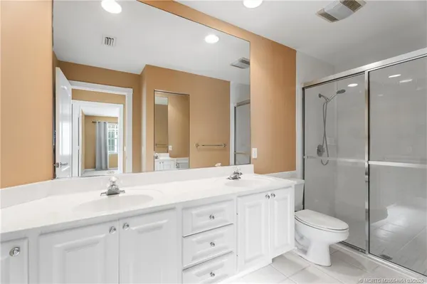 a bathroom with a double vanity sink toilet mirror and shower