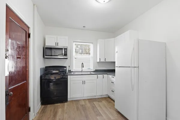 a kitchen with white cabinets and appliances