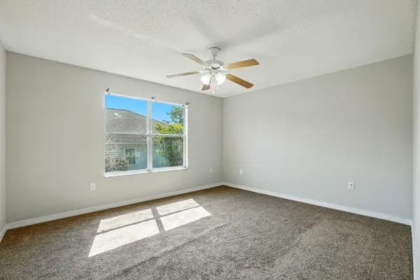 an empty room with a window and a fan