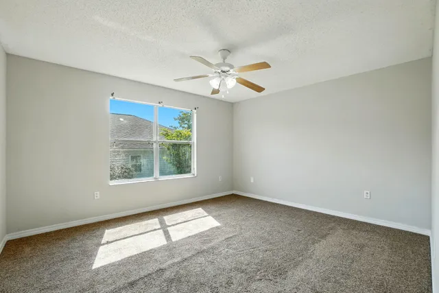 an empty room with a window and a fan