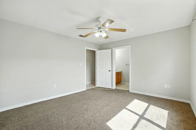 a view of an empty room and chandelier fan
