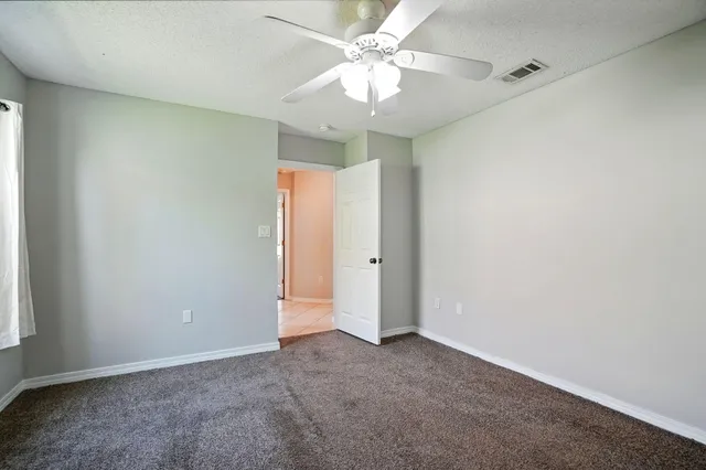 an empty room with a ceiling fan and a window