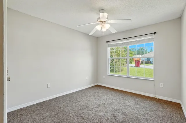 an empty room with windows and ceiling fan