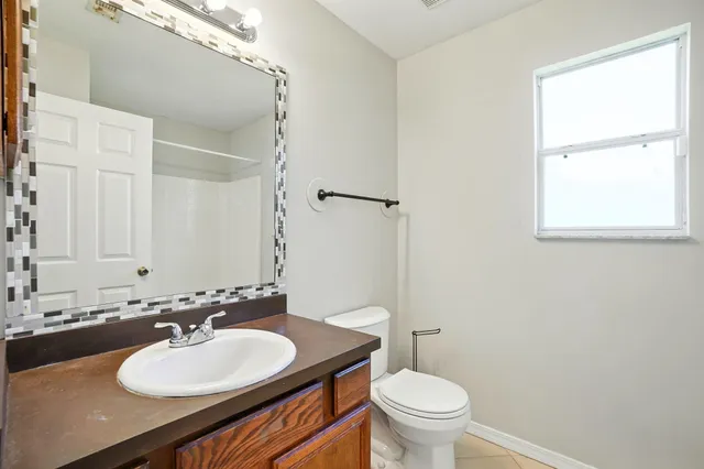 a bathroom with a sink a toilet a mirror and a window