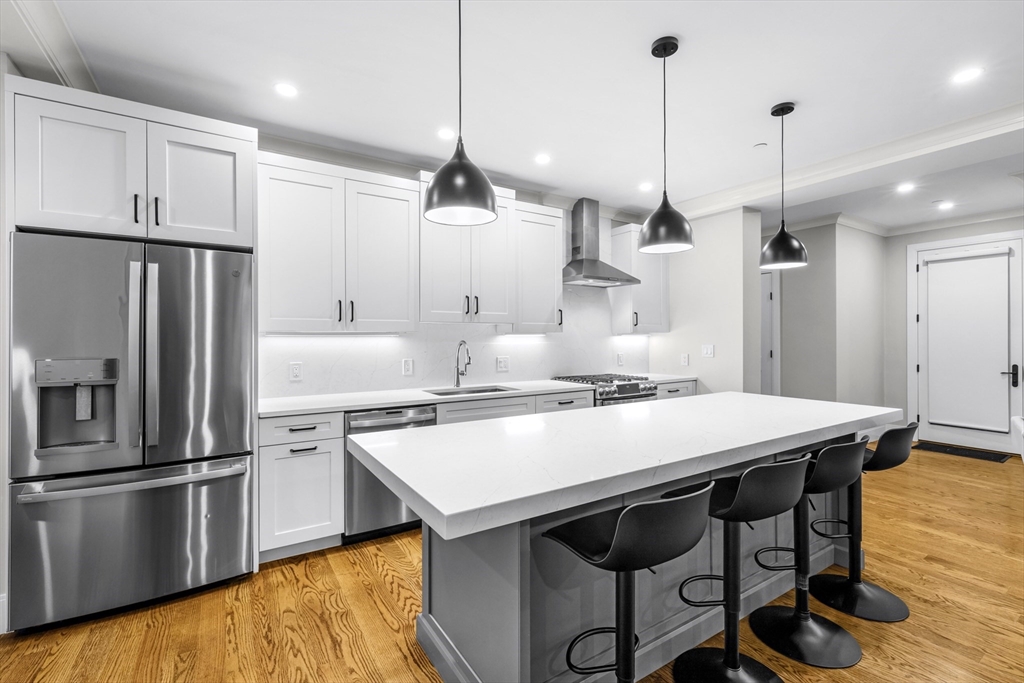 a kitchen with granite countertop a table chairs stainless steel appliances and wooden floor