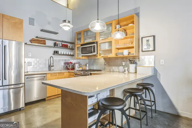 a kitchen with stainless steel appliances a table and chairs in it