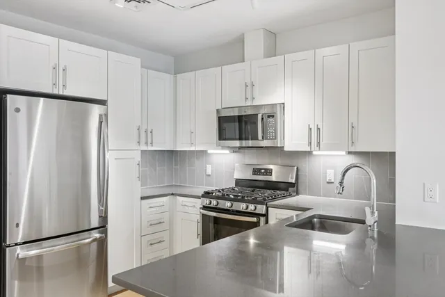 a kitchen with white cabinets and stainless steel appliances