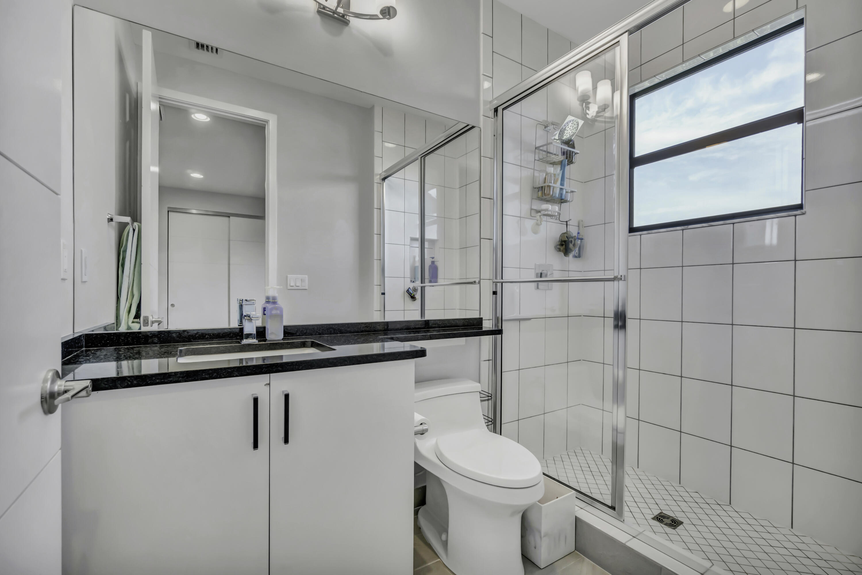 17081 Five Waters Avenue Boca Raton, FL 33496 - Photo 70 of 109 a bathroom with a granite countertop sink a toilet and a mirror