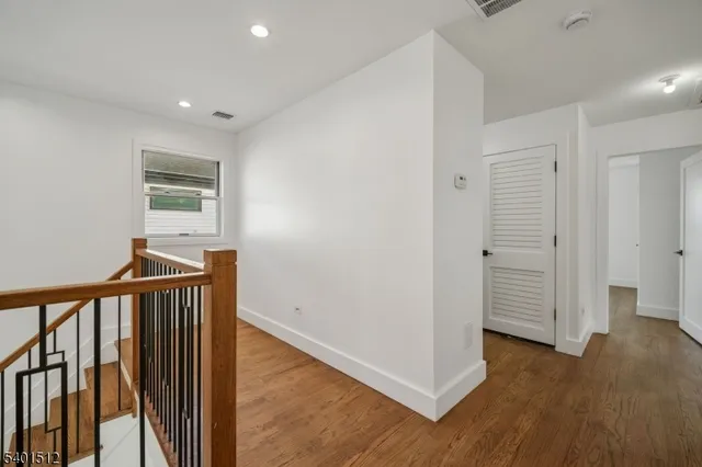 a view of a hallway with wooden floor and stairs