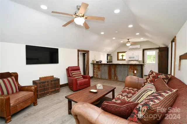 a living room with furniture a flat screen tv and kitchen view