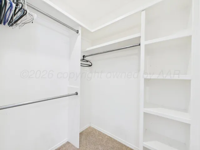 a spacious bedroom with a bed and lamp