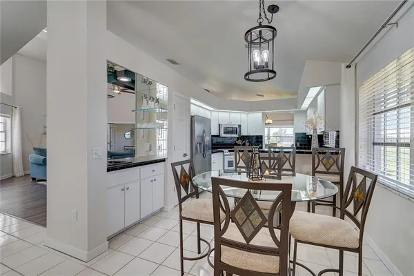 a kitchen with stainless steel appliances kitchen island granite countertop a dining table chairs and a refrigerator