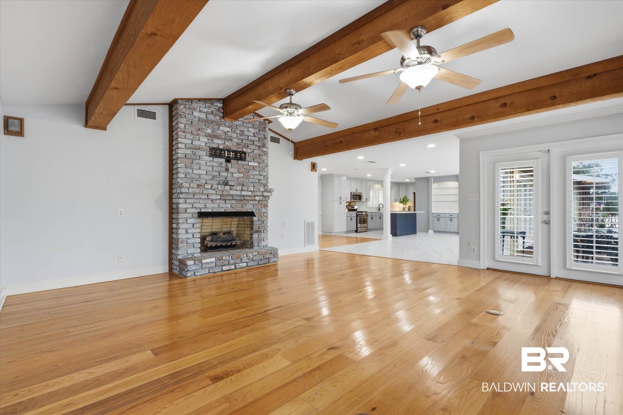 3801 Point Road Mobile, AL 36619 - Photo 7 of 55 Spacious living area featuring polished wood flooring, exposed wood beams, a stone-clad fireplace, and dual ceiling fans