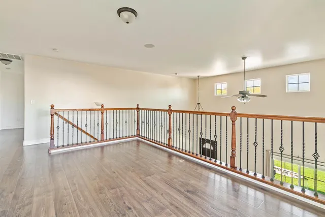 an empty room with wooden floor fan and windows