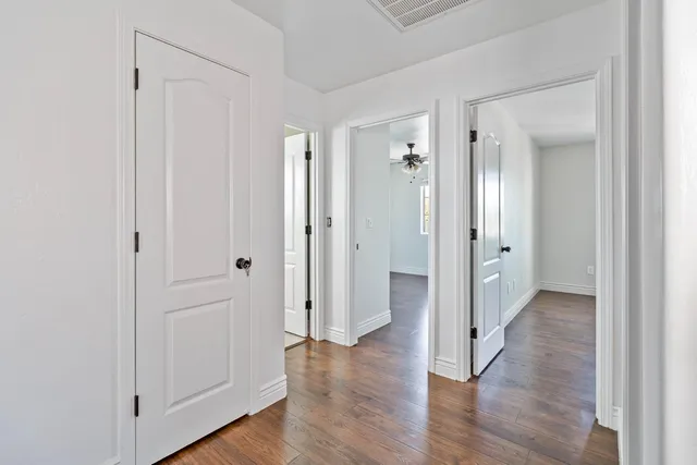 an empty room with wooden floor ceiling fan and windows