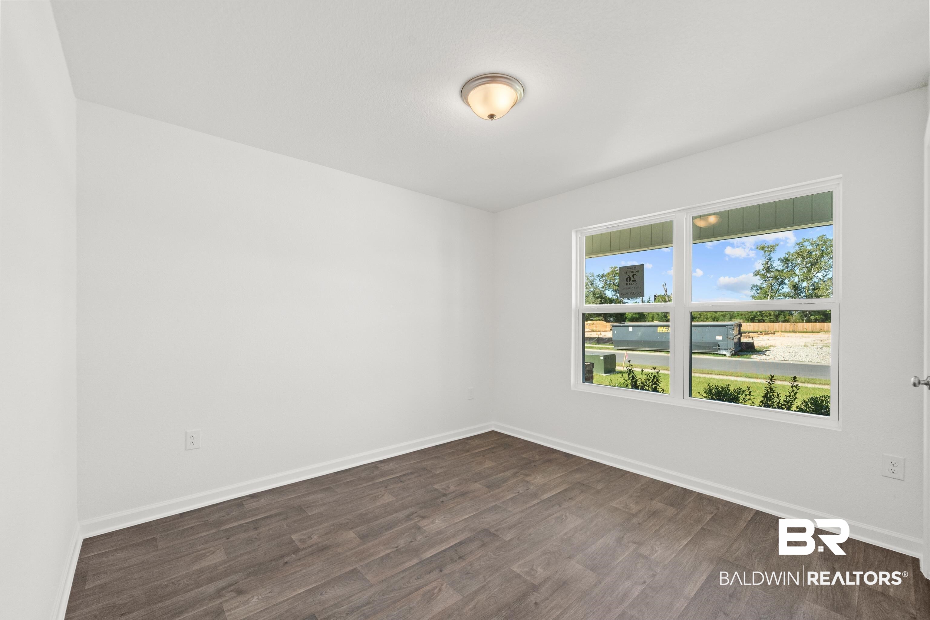 Room featuring wood-finish flooring, white walls, and a single window with white trim