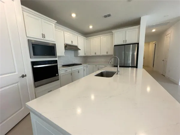 a kitchen with granite countertop white cabinets and refrigerator