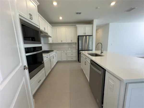 a kitchen with white cabinets and black appliances