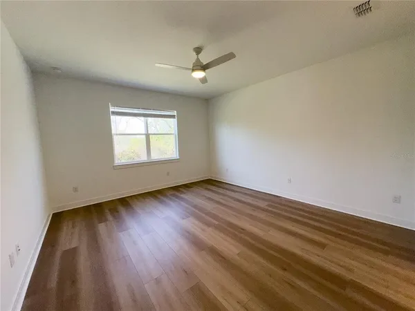 an empty room with a window and a ceiling fan