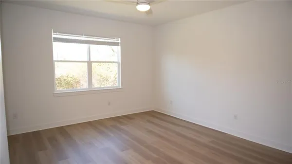 an empty room with wooden floor closet and fan
