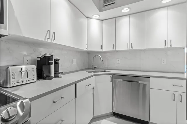 a kitchen with white cabinets and sink