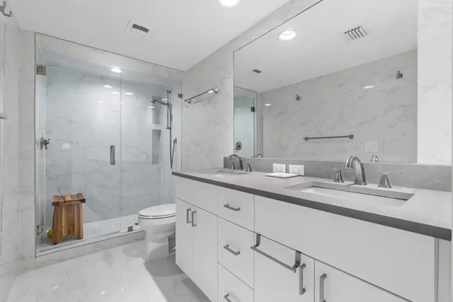 a spacious bathroom with a double vanity sink toilet mirror and shower