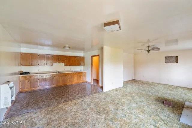 a view of a kitchen with kitchen island a sink wooden floor and a refrigerator