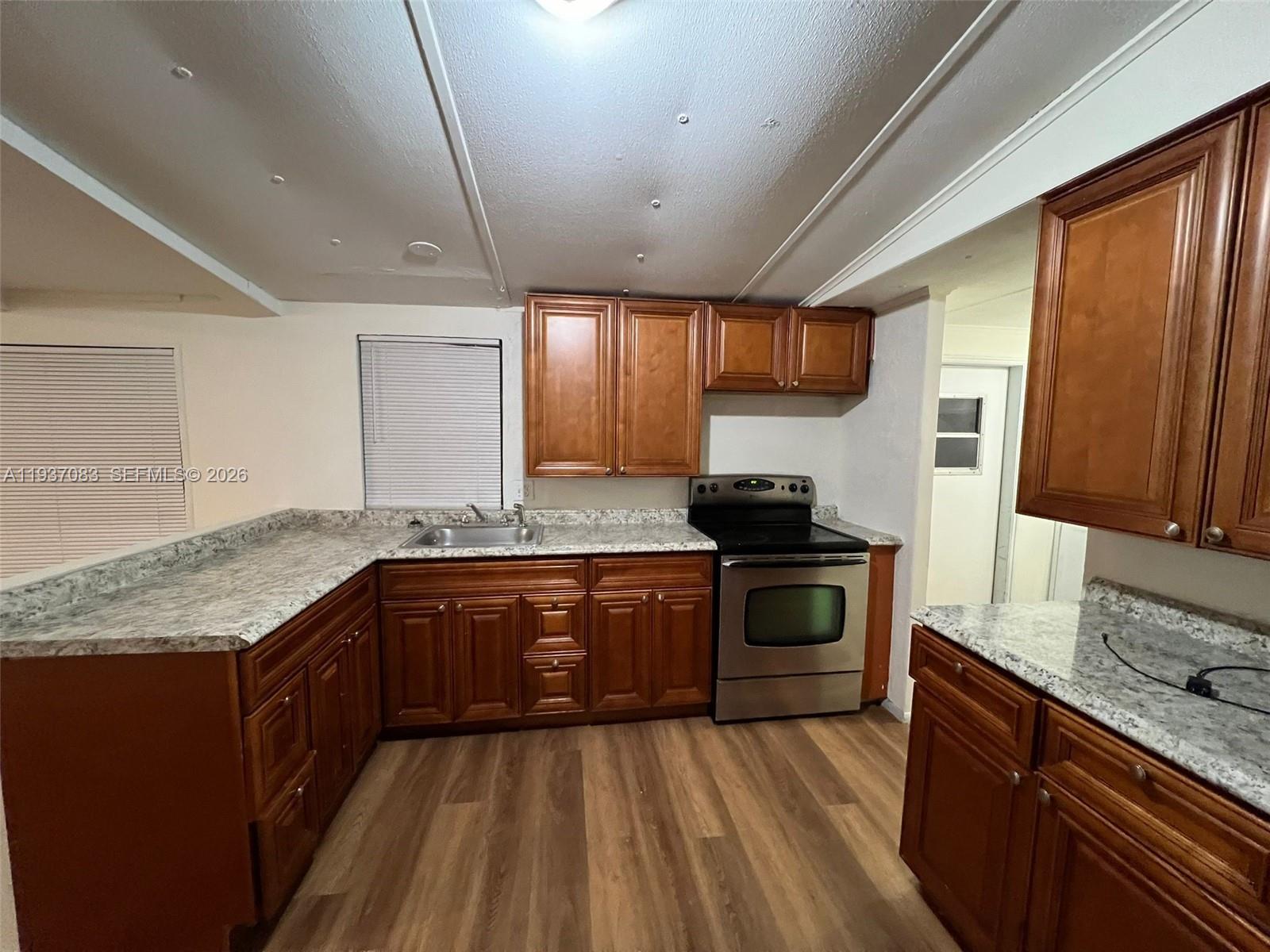 10492 South 228th Lane, Unit A Boca Raton, FL 33428 - Photo 3 of 37 a kitchen with granite countertop wooden cabinets and a stove top oven