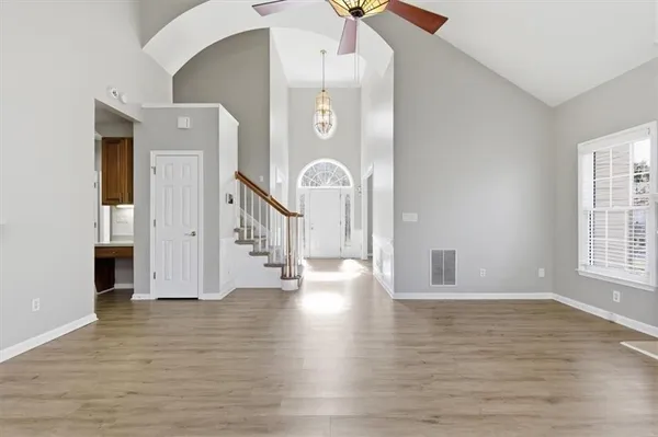 an empty room with wooden floor fan and windows