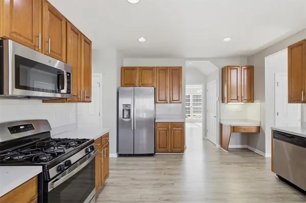 a kitchen with stainless steel appliances granite countertop wooden cabinets a stove a sink a refrigerator and a refrigerator