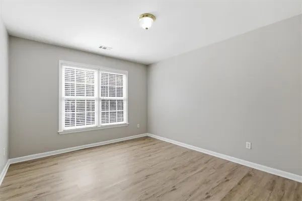 a view of an empty room with wooden floor and closet