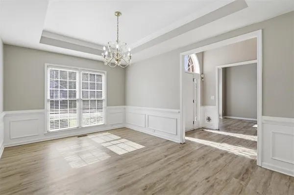 a view of a hallway with wooden floor and a chandelier